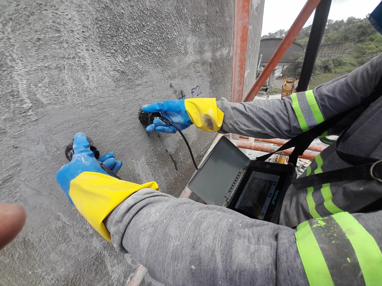 Profissional realizando leitura com equipamento em parede de concreto